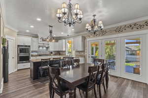 Dining room with ornamental molding, laminate wood-style flooring, a textured ceiling, recessed lighting, and a chandelier