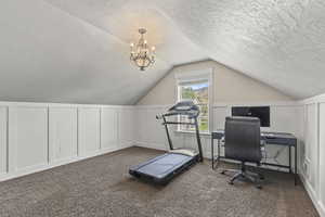 Bonus room featuring a decorative wall, a textured ceiling, vaulted ceiling, a chandelier, and carpet