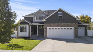 Craftsman-style house featuring driveway, roof with shingles, and stone siding