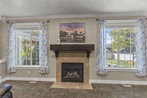 Detailed view of carpet flooring, a fireplace with flush hearth, and crown molding