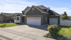 View of front of house featuring driveway, a gate, stone siding, and a shingled roof