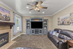 Living room featuring ornamental molding, carpet floors, recessed lighting, a fireplace with flush hearth, and ceiling fan