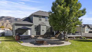 Rear view of house with a fenced backyard, a shingled roof, a gazebo, a hot tub, and a patio area