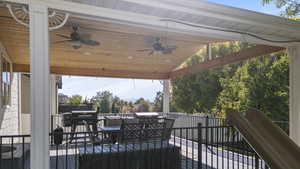 Covered vaulted deck with a ceiling fan, outdoor dining space, and a grill