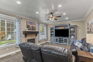 Carpeted living area with crown molding, a fireplace, a ceiling fan, and recessed lighting