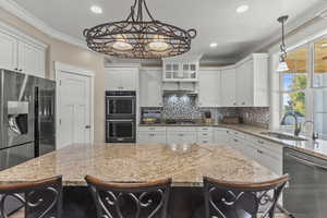 Kitchen with a kitchen bar, appliances with stainless steel finishes, decorative backsplash, light stone countertops, and ornamental molding