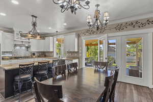 Dining space with laminate wood-type flooring, crown molding, recessed lighting, a chandelier, and a textured ceiling