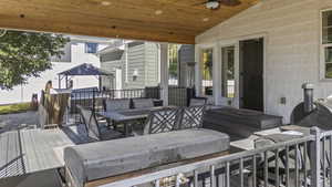 Covered vaulted deck featuring outdoor dining space, an outdoor hangout area, and a ceiling fan