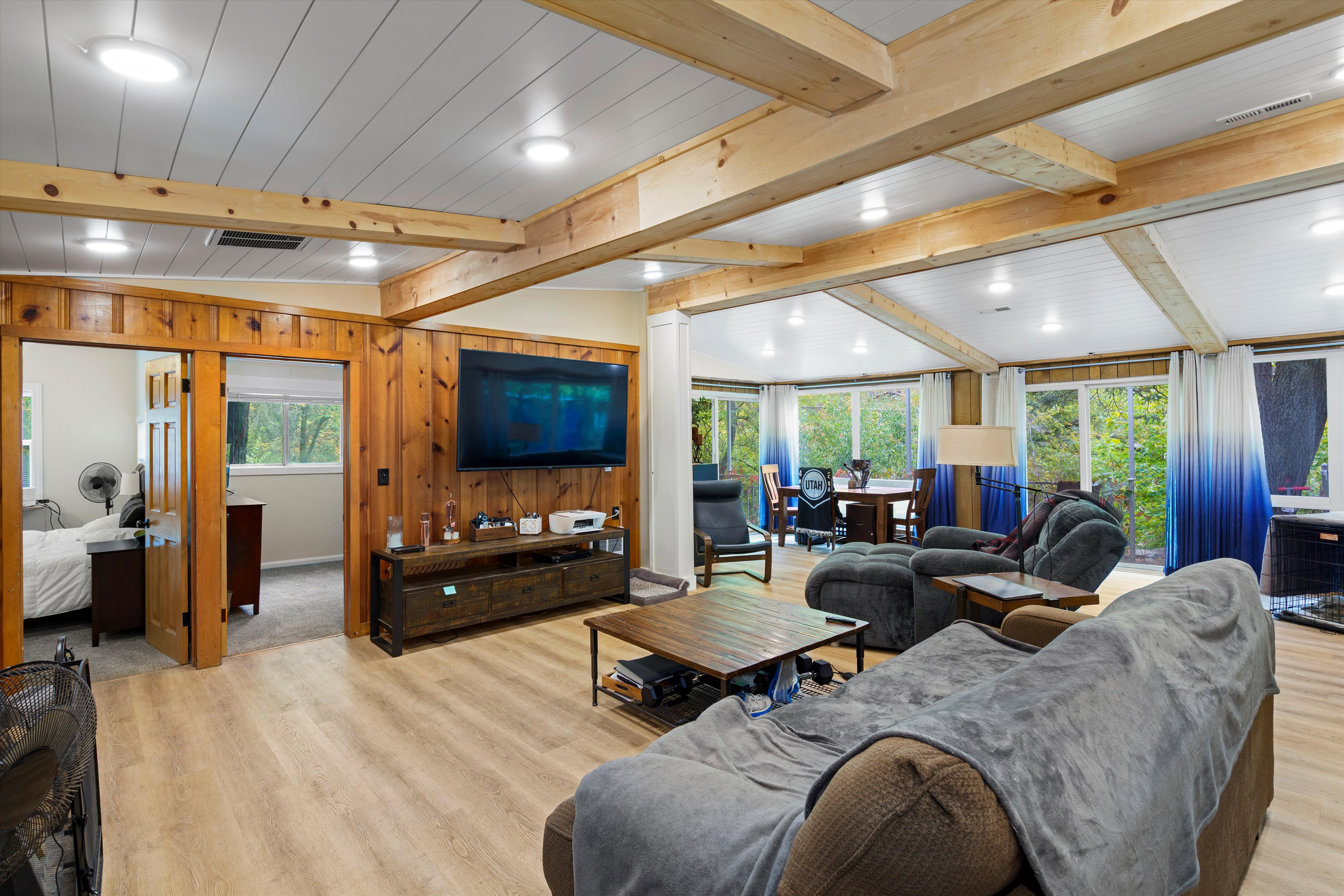 Living area with wood walls, light wood-type flooring, beamed ceiling, and recessed lighting