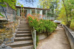 View of front of house featuring stairway, a wooden deck, and a sunroom