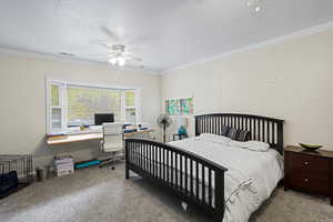 Bedroom featuring carpet floors, ornamental molding, a ceiling fan, a desk, and a textured ceiling