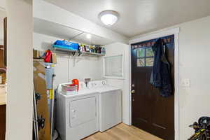 Washroom with wood finished floors and washing machine and dryer