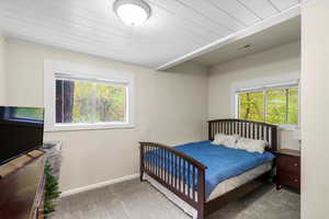 Carpeted bedroom with baseboards and wood ceiling