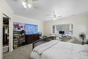 Bedroom with ornamental molding, ceiling fan, carpet flooring, a closet, and a desk