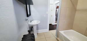 Full bathroom with light tile patterned floors and a textured wall