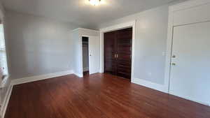 Unfurnished bedroom with dark wood-type flooring, a textured ceiling, and a closet