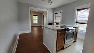 Kitchen featuring stainless steel electric range oven, a kitchen island, dark wood-style floors, ceiling fan, and dark brown cabinetry