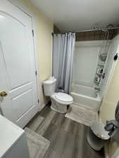 Full bath featuring shower / tub combo with curtain, dark wood-type flooring, and vanity