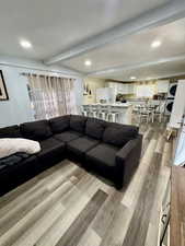 Living room featuring beam ceiling, light wood finished floors, and recessed lighting