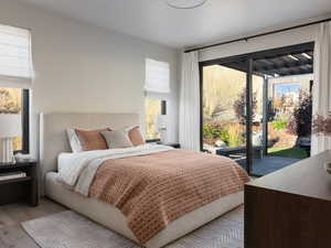 Bedroom with wood finished floors, multiple windows, and access to outside