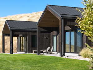 Rear view of house featuring a metal roof, a patio area, a standing seam roof, and a yard
