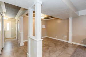 Hallway from main exterior entrance, past the half bath and into main dining area with tile patterned flooring, crown molding, stairs, and a textured ceiling