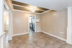Main dining area with tile patterned flooring, crown molding, stairs, and a textured ceiling