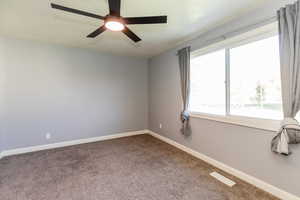 Carpeted empty room with a ceiling fan and a textured ceiling