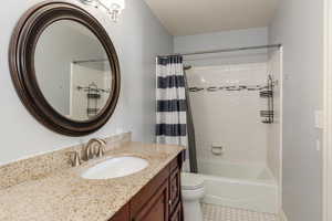 Main bathroom off of the master bedroom featuring shower, vanity, and light tile patterned flooring
