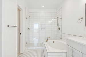 Primary Bathroom featuring a stall shower, a garden tub, vanity, light tile patterned flooring, and recessed lighting