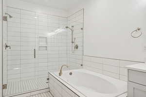 Grand Primary Bathroom featuring a stall shower, a garden tub, and vanity