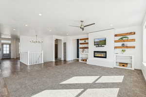 Unfurnished great room with carpet floors, a fireplace, built in features, recessed lighting, and a ceiling fan