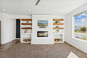 Unfurnished living room featuring carpet, recessed lighting, and a large fireplace