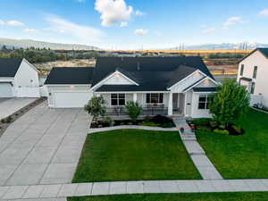 View of front of house with a porch, a shingled roof, concrete driveway, board and batten siding, and a mountain view