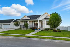 Modern inspired farmhouse with a porch, board and batten siding, a shingled roof, and driveway