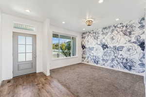 Foyer entrance with wood finished floors, recessed lighting, an accent wall, and wallpapered walls