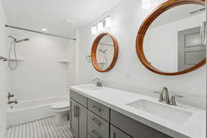 Bathroom with shower / washtub combination, double vanity, light tile patterned flooring, and recessed lighting