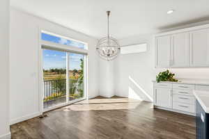 Unfurnished dining area featuring medium wood-style flooring, a chandelier, recessed lighting, and a water view