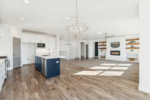 Kitchen featuring a fireplace, open floor plan, white cabinetry, recessed lighting, and dark wood-type flooring