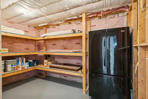View of storage area includes refrigerator and shelving.
