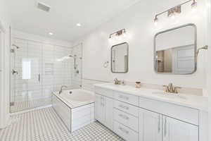 Grand Primary Bath with a stall shower, a bath, double vanity, recessed lighting, and light tile patterned floors