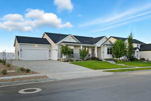 View of front of home featuring driveway, a porch, a front lawn, a garage, and board and batten siding