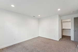 Unfurnished bedroom with a walk in closet, carpet flooring, and recessed lighting