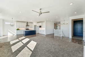 Unfurnished living room featuring a chandelier, recessed lighting, medium wood-style floors, a barn door, and a ceiling fan