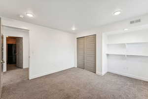 Unfurnished bedroom with light colored carpet, a closet, and recessed lighting