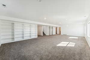 Family Room featuring carpet floors, stairs, and recessed lighting, built in shelving