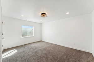Carpeted empty room with baseboards and recessed lighting