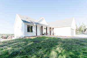 Modern farmhouse featuring a porch, a front yard, board and batten siding, roof with shingles, and a garage