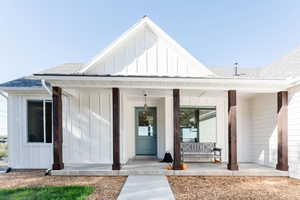 Entrance to property featuring board and batten siding, roof with shingles, and a porch