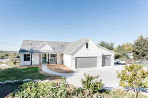 Modern farmhouse style home with board and batten siding, a porch, roof with shingles, concrete driveway, and a front lawn